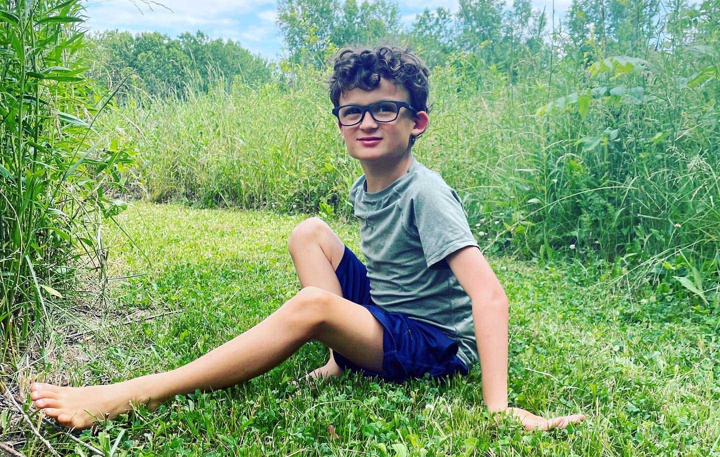 Beau sitting in a grassy field on a sunny day